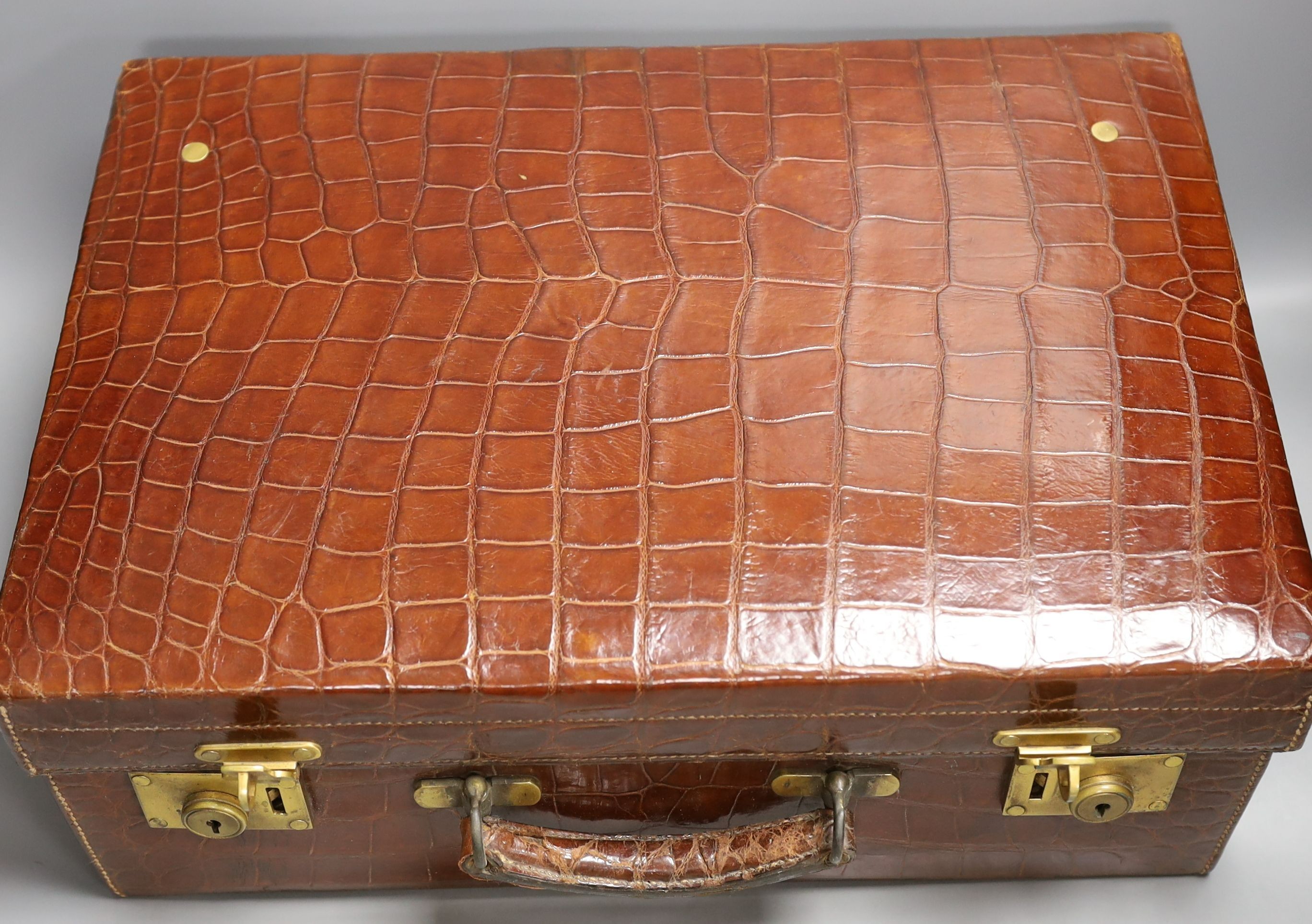 Two early 20th century crocodile hide suitcases, largest 48cms wide x 33 cms deep x 19cms high.